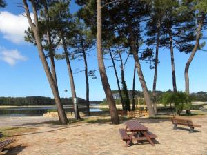 a picnic table and benches in a park next to trees at Appartement Le Maro in Saubusse +8 photos