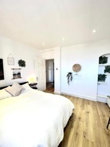 a white bedroom with a large bed and wooden floors at Bright & Spacious 1 bed steps from Hyde Park in London