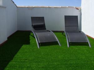 duas cadeiras vazias sentadas numa sala com relva verde em Apartamento San Anton em La Iruela