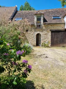 an old stone house with a gate and flowers at La Parenthèse Campagnarde in Richarville