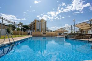 een groot zwembad met een gebouw op de achtergrond bij Hotel Balneario de Chiclana in Chiclana de la Frontera