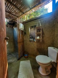 a bathroom with a white toilet in a room at Pousada Raiz Forte in Caraíva