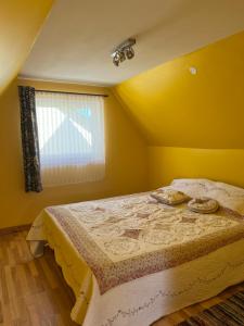 ein Schlafzimmer mit einem Bett in einem gelben Zimmer in der Unterkunft Brīvdienu namiņš in Ludza