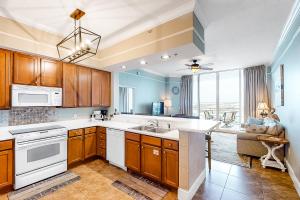 a kitchen with wooden cabinets and a large window at Destin West Resort - Gulfside PH03 in Fort Walton Beach