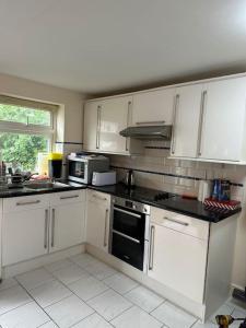 a kitchen with white cabinets and a stove top oven at Amazing Gantshill Studio Annexe & Free Parking in Redbridge