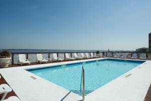 a swimming pool with chairs and the ocean in the background at Palm Beach Club 2-225 in Pensacola Beach