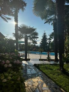 a stone walkway with palm trees and a pool at Holiday House Serenity in Malinska