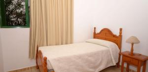 a bedroom with a bed and a table and a window at Apartamento Bajo en el Tamaduste Zona Privilegiada in Tamaduste