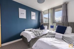 two beds in a room with a blue wall at Luxury 2-bed In central MK By Valore Property Services in Milton Keynes