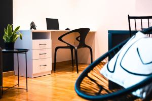 an office with a desk and a chair and a tennis racket at Monochromatic Apartment in Prishtinë