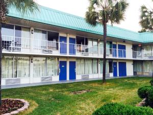un edificio de apartamentos con puertas azules y palmeras en Motel 6-Tifton, GA, en Tifton