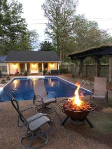 a fire pit in front of a pool with two chairs at Pool House in Clarksdale
