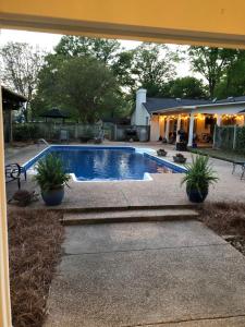 a swimming pool with two potted plants in front of a house at Pool House in Clarksdale