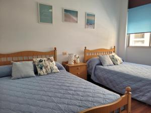 a bedroom with two beds and a night stand with tworams at PIso de 3 habitaciones en centro de Miño in Miño