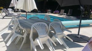 una mesa con sillas y una sombrilla junto a la piscina en Villa avec Piscine chauffée et parc arboré située à 100 m de la Plage et Forêt sans vis à vis, en Saint-Trojan-les-Bains