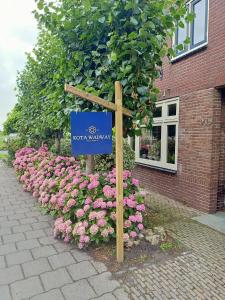 a sign in front of a bunch of pink flowers at Kota Wadway in Spanbroek