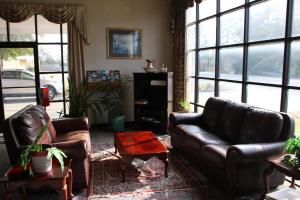 uma sala de estar com mobiliário de couro e janelas grandes em American Inn of Selma em Selma