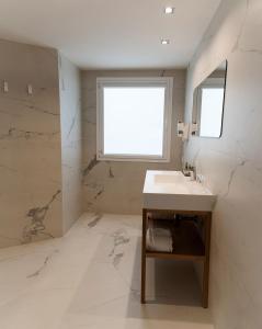 baño blanco con lavabo y ventana en Hotel Agaró, en Chipiona