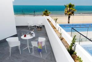 balcón con mesa y sillas y la playa en Hotel Agaró en Chipiona