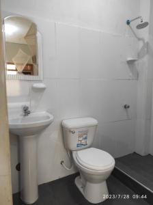 a white bathroom with a toilet and a sink at La Casa de Joan in Máncora