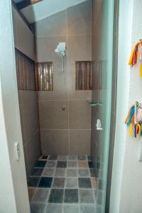um chuveiro com uma porta de vidro e um piso de azulejo em Cabana na árvore na Bahia! Para viver uma experiência de hospedagem pertinho da praia em Maraú