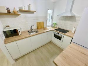 Una cocina con gabinetes blancos, un fregadero y un microondas. en Apartamento El Sereno, en Teruel