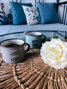 dos tazas de café y una flor blanca en una mesa de mimbre en Viesu māja Virši, en Stropi