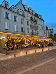 un grand bâtiment avec des personnes assises à l'extérieur dans l'établissement Le Bali Cosy House - T2 lumineux et moderne en plein centre ville de Maisons-Alfort, à Maisons-Alfort