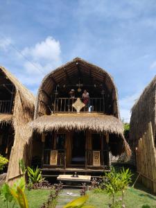 two people standing on a balcony of a hut at Mahkota Atia Bungallow in Praya