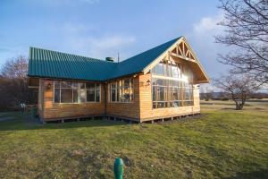 a wooden house with a green roof on a field at Glamping Río Serrano - Caja Los Andes in Puerto Natales