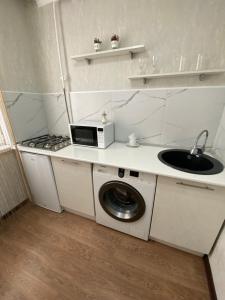 cocina con fregadero y lavadora en 1 ком квартира в районе City center, en Uralsk