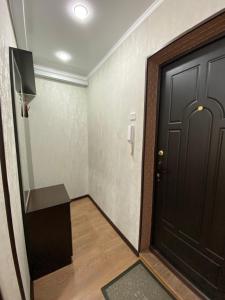 korytarz z czarnymi drzwiami i drewnianą podłogą w obiekcie 1 ком квартира в районе City center w mieście Uralsk