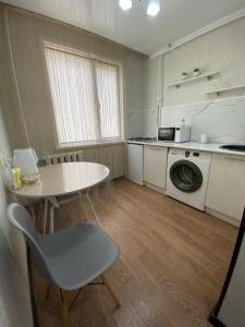 a kitchen with a table and a table and a washing machine at 1 ком квартира в районе City center in Uralsk