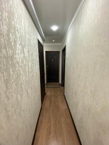 pasillo con puerta negra y suelo de madera en 1 ком квартира в районе City center, en Uralsk