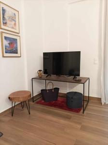 a living room with a television and a table at Eutuxia Sea&Mountain Apartment - Tsoutsouros in Tsoutsouros