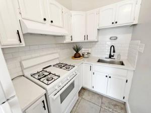 cocina blanca con fogones y fregadero en Lovely 2bd in Mount Adams near Downtown and OTR en Cincinnati