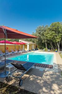 - une piscine avec des chaises et un parasol rouge dans l'établissement Logis La Bastide De Grignan Hotel & Restaurant "La Chênaie", à Grignan