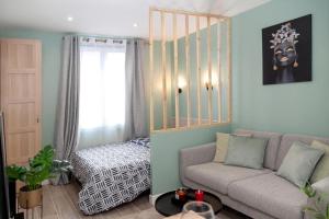 een woonkamer met een bank en een bed bij Studio cozy, proche paris in Pré Saint Gervais