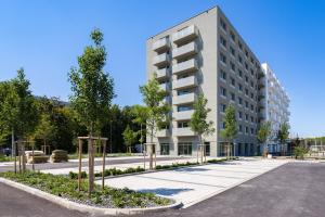 um edifício de apartamentos com árvores em frente a uma rua em 2 room Apartment, new building, near Airport, Ovocné sady, em Prievoz