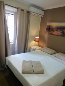 ein Schlafzimmer mit einem weißen Bett mit einer Lampe und einem Fenster in der Unterkunft Aliciamar E by Casas de Setúbal in Setúbal