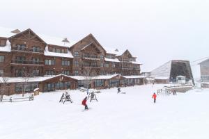 um grupo de pessoas a esquiar na neve em frente a um alojamento de turismo selvagem em Jay Peak Village Home 367A&B em Jay