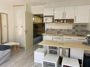 a kitchen with white cabinets and a table and chairs at Home Sweet Sauze - Chaleureux appartement - Lumineux et calme - Vue sur la montagne in Enchastrayes