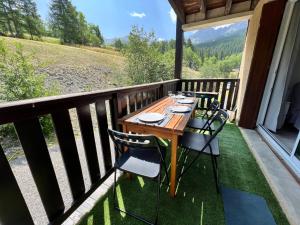 a wooden table and chairs on a balcony with a view at Home Sweet Sauze - Chaleureux appartement - Lumineux et calme - Vue sur la montagne in Enchastrayes