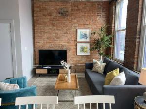a living room with two couches and a brick wall at SWIZZLE Explore OTR and Downtown from Rhinegeist in Cincinnati