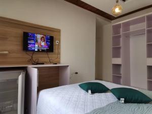 ein Schlafzimmer mit einem Bett und einem Fernseher an der Wand in der Unterkunft Chambre de luxe chez FOUR IN ONE Résidence in Limbe