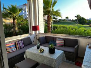 アシラにあるMarina golf ASSILAH vue verteのヤシの木のあるバルコニーにあるソファとテーブル