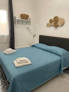 a bedroom with a blue bed with towels on it at Le lumie in Pachino