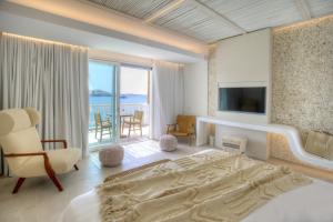 Icon Mykonos في Megali Ammos: غرفة نوم بسرير وتلفزيون وشرفة