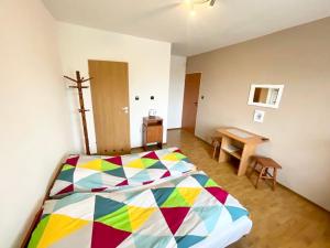 Un dormitorio con una cama colorida y una mesa de madera. en Promyk, en Władysławowo