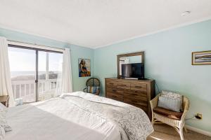 a bedroom with a bed and a television and a window at Dunescape Villas 221 in Atlantic Beach